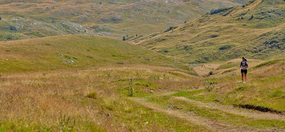 Žena sa flašicom vode trči u prirodi